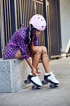 Beautiful young woman put on roller skates and tying shoelaces