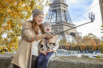 happy mother and daughter taking selfie on embankment in Paris