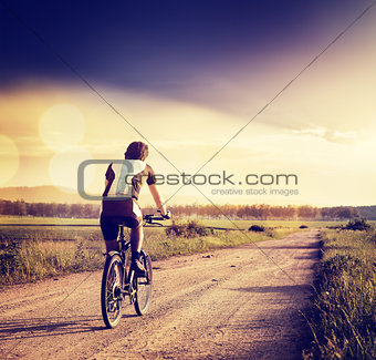 Cyclist Riding a Bike on Country Road. Toned Photo