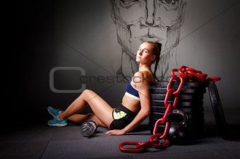 Young attractive woman sit on the flor with sports equipment