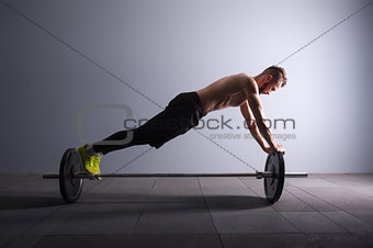 one man exercising fitness plank position on the barbel exercises in studio silhouette dark key