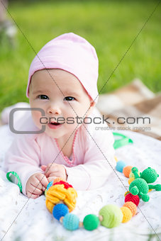 Baby girl crawling on the grass with sling beads