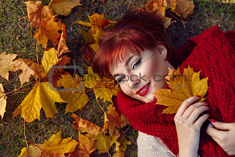 Red hair girl lying with autumn maple leaf