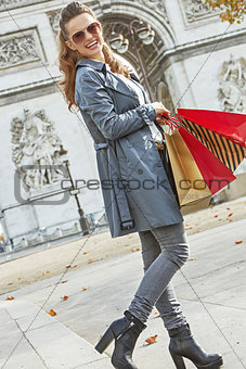 happy trendy woman in trench coat shopping in Paris, France