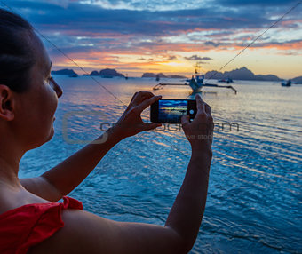 Woman taking pictures at sunset