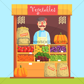 Vendor Behind Market Counter With Assortment Of Vegetables