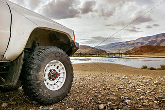 Big SUV car wheel on backdrop of lake