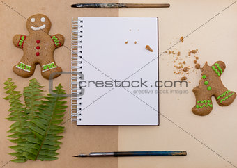 Mock up decorated Christmas gingerbread biscuits and blank notepad with craft paper background