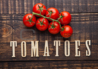 Fresh tomatoes on wooden board with letters below