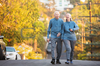 Laughing couple walking along street on hill