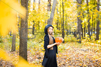 Halloween Witch with Pumpkin in a forest.