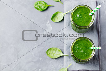 Spinach smoothie Healthy drink in glass jar on grey stone background. Copy space Top view