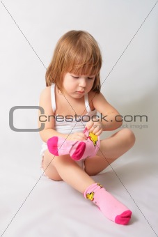 Small girl is puting on the socks