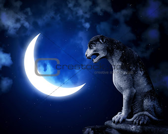 Ancient lion statue and crescent on night sky background