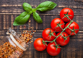 Fresh tomatoes with basil and spices jar on grunge board
