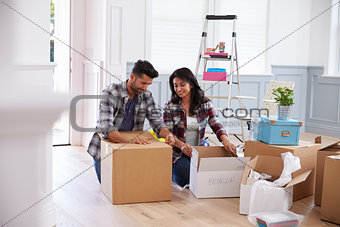 Hispanic Couple Moving Into New Home And Unpacking Boxes