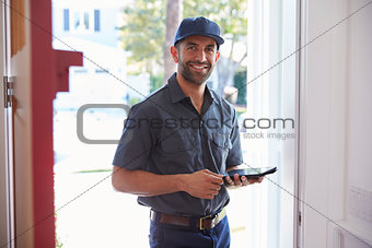 Courier Standing At Front Door With Digital Tablet