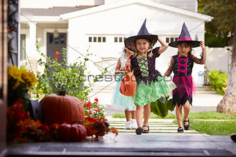 Three Children In Halloween Costumes Trick Or Treating