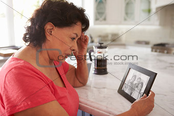Senior Hispanic Woman At Home Looking At Old Photograph