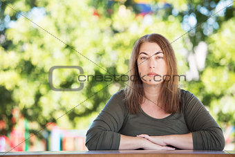 Serious woman seated at table outside