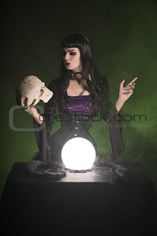 Beautiful witch holding human skull in her hand 