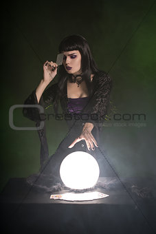 Attractive fortune teller with playing cards and crystal ball 