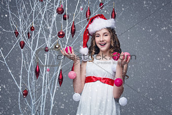 Beautiful girl standing near tree with christmas decorations