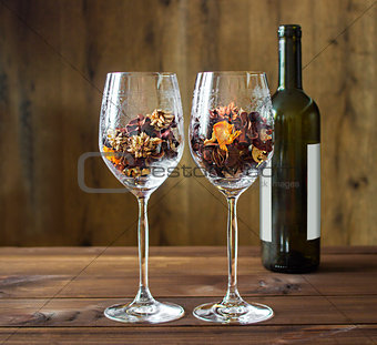 Autumn leaves in a wine glass and wine bottle on wooden table background