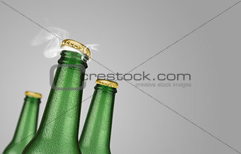 Three green beer bottles on grey background