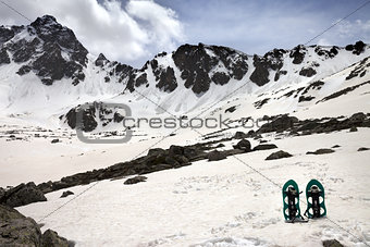 Snowshoes in snow mountains in sun spring day