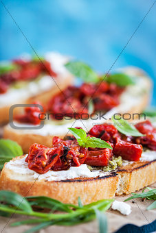 Bruschetta with cream cheese, pesto, fresh basil and sun dried t