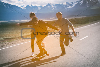 Group of friends run, laugh and having fun. The guy on longboard.