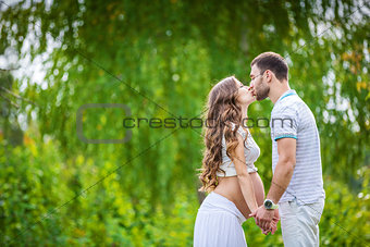 Happy young couple expecting baby in summer park