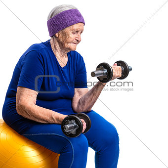 Senior woman working out with with dumbbells while sitting on fitball