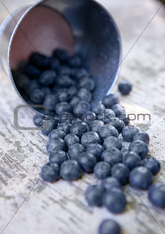 Blueberries in small steel bucket on grunge wooden board