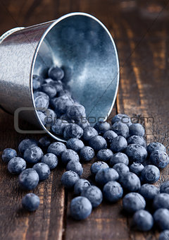Blueberries in small steel bucket on grunge wooden board