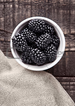 Blackberry in white bowl  on grunge wooden board