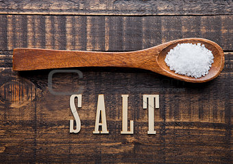 Salt on wooden spoon with letters below