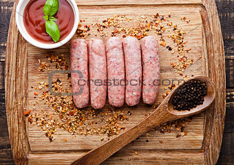 Raw beef sausages with pepper spoon and sause on board