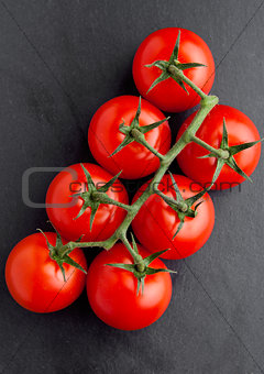 Fresh organic tomatoes on black stone board 