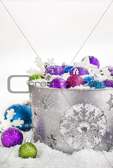 Christmas balls in snow covered bucket 