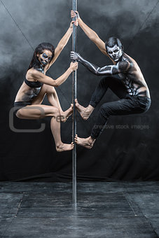 Posing of pole dance couple in dark studio