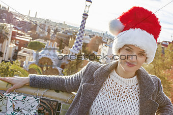 traveller woman in Santa hat at Guell Park sitting on bench
