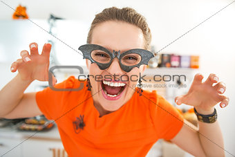 smiling young woman in Halloween decorated kitchen frightening