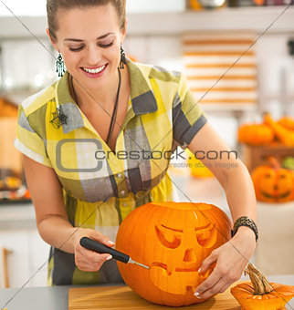 happy housewife carving a big orange pumpkin Jack-O-Lantern