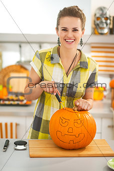 woman in kitchen carving big orange pumpkin Jack-O-Lantern