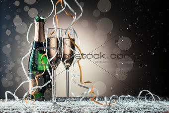 Champagne bottle and two wineglasses on table covered snow