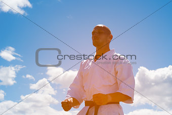 Man in kimono meditating on sky background.