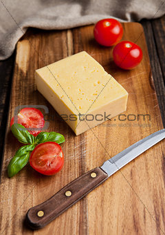 Cheese with tomatoes and basil on wood with knife