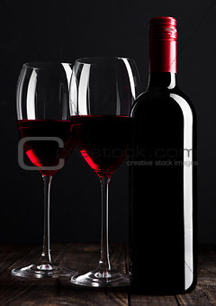 Red wine bottle and glasses on wooden table black
